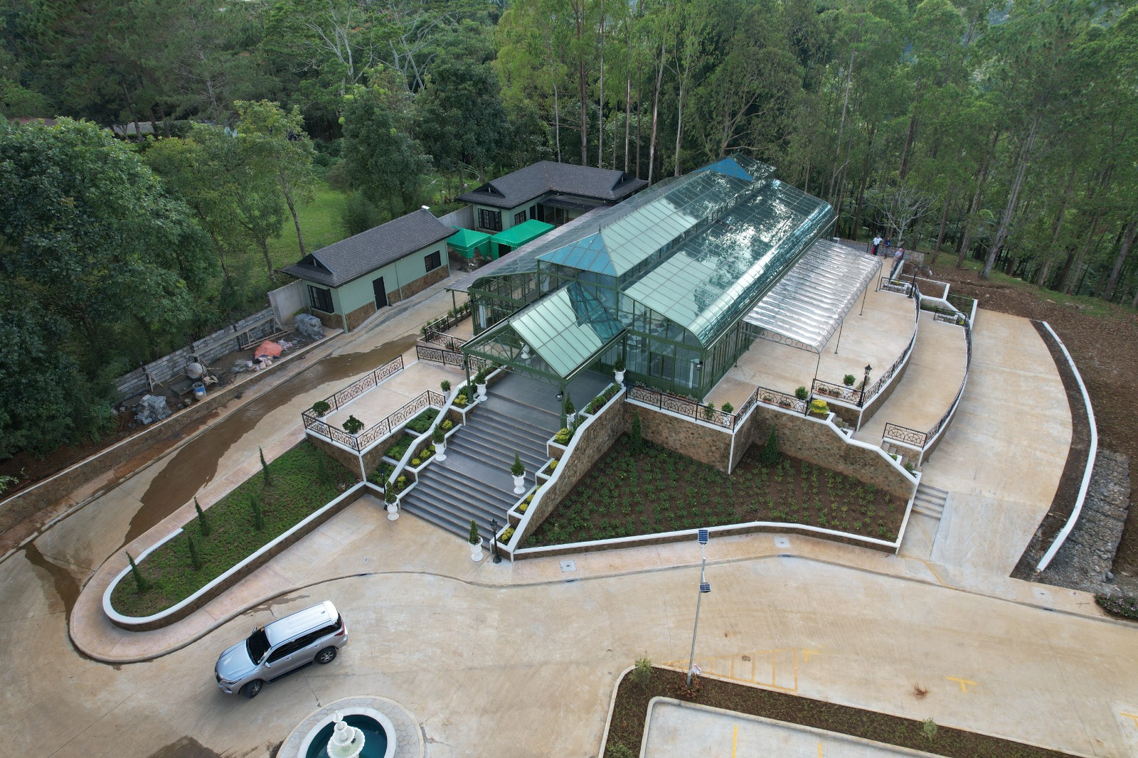 Aerial rendering of a hillside glass house venue with parking and broad steps