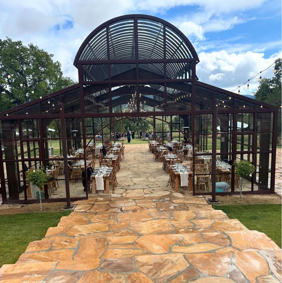 Front entrance rendering of the glass house venue with arched glazing and formal dining setup